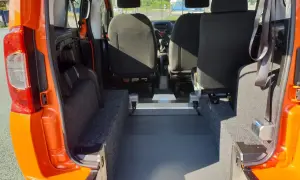 Interno di un Fiat Qubo arancione, con sedili posteriori e ampio spazio per il bagagliaio. Le dimensioni del bagagliaio sono ideali per trasporti.