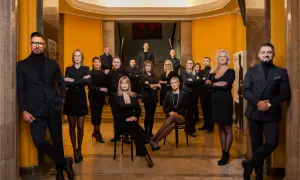 Grupa profesjonalistów w czarnych strojach pozuje w eleganckim wnętrzu.