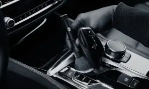 Rękawiczka czyści szczoteczką błyszczące piano black wokół dźwigni biegów.