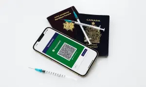 Gotowi na podróż? Paszporty, telefon z potwierdzeniem szczepień i strzykawki symbolizują przygotowania do wyjazdu.