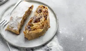 Due fette di strudel di mele su un piatto, cosparse di zucchero a velo. Un dolce invitante pronto da gustare.