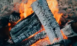 Płonące polana, z których unosi się biały **popiół**, tworzą ciepły, pomarańczowy blask.