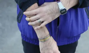 Combinaciones de pulseras y anillos dorados y plateados en brazos y muñecas, con reloj digital.