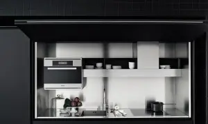 Cocinas invisibles: un horno Miele, fregadero y placa de inducción integrados en un diseño minimalista de acero inoxidable y gabinetes negros.