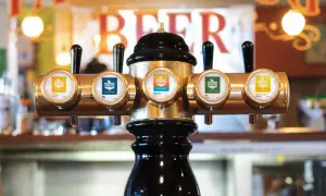 Błyszczące kraniki piwne z etykietami, w tym "Hazy IPA", w pubie.