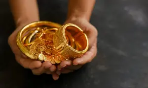 Manos sostienen un tesoro de joyas de oro, pulseras y monedas, un reflejo de las curiosidades del oro y su valor eterno.