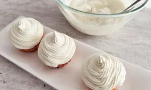 Trzy deserki z kremem z mascarpone i białej czekolady, obok miska z kremem.