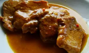 Soczysta szynka pieczona w plastrach, polana aromatycznym sosem, idealna na obiad.