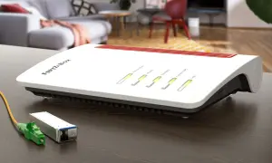 Router FRITZ!Box z zielonym złączem światłowodowym obok. Gotowy do szybkiego internetu.