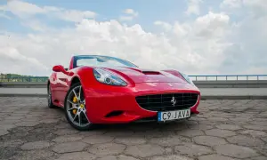 Czerwone Ferrari California z żółtymi zaciskami hamulcowymi na tle błękitnego nieba z chmurami.