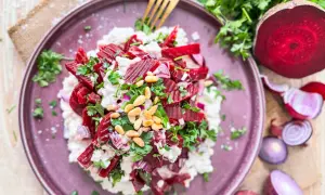 Rote Bete Salat nach Omas Art: ein cremiger Salat mit Rote Bete, Zwiebeln, Pinienkernen und frischer Petersilie, serviert auf einem lila Teller.