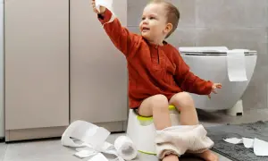 Bambino di 4 anni sul vasino, con rotoli di carta igienica sparsi. Un piccolo disastro, ma un grande passo verso l'indipendenza!