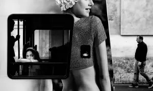 Un ritratto che evoca i grandi fotografi di moda famosi: una giovane donna con cuffia da nuoto, riflessa in un finestrino, mentre un uomo cammina sullo sfondo.