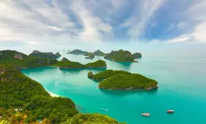 Grüne Inseln im türkisfarbenen Meer, ein Paradies für die beste Reisezeit Asien. Boote gleiten auf dem Wasser.
