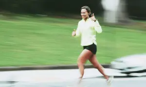 Donna sorridente corre con pollice in su, indicando un ottimo ritmo medio corsa.