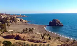 La playa Peñón del Cuervo, con su icónica roca en el mar, invita a pasear por su arena oscura bajo un cielo azul.