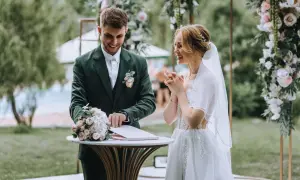 Para młoda podczas ceremonii ślubnej na tle dekoracji z kwiatów.