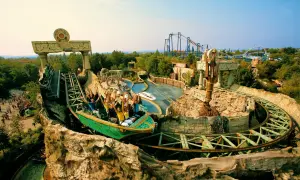 Attrazione acquatica con barca che scende da un'altura, tra rovine e vegetazione. Un'idea di cosa vedere a Bussolengo per divertirsi.
