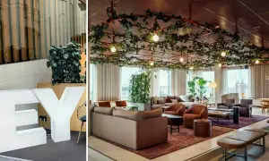 Stora vita bokstäver "EY" och en modern lounge med växter i taket, perfekt för att jobba hybrid.