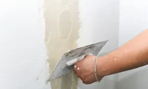 Hand mit Glättekelle bessert Rauputz aus.
