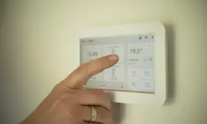 Dłoń dotyka ekranu termostatu, gdzie widnieje 19,5°C. Użytkownik szuka rozwiązania problemu: "piec nie osiąga zadanej temperatury forum".