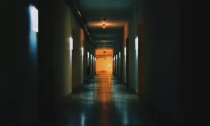 Un corridoio buio con luci al neon che cercano di rendere luminoso lo spazio. La prospettiva crea un senso di profondità.