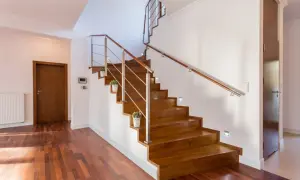 Escaleras de madera sin contrahuella, con barandilla de metal y madera, y luces empotradas. Un diseño moderno y elegante.