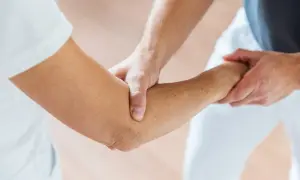 Physiotherapeut hilft beim Ellenbogen mobilisieren nach OP. Sanfte Berührung zur Wiederherstellung der Beweglichkeit.