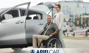 Coppia felice vicino a un'auto, lui in carrozzina. La vendita auto acquistata con Legge 104 dopo 2 anni è un nuovo inizio.