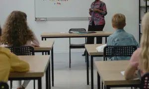 Grundschüler sitzen aufmerksam im Klassenzimmer, während eine Lehrerin eine Vertretungsstunde gibt.