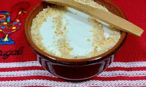 Delicioso serradura portuguesa en cuenco de barro, espolvoreado con galleta triturada y una cuchara de madera.