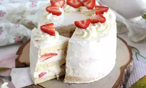 En vacker italiensk tårta med mascarpone, fylld med jordgubbar och täckt med fluffig grädde och färska jordgubbsbitar.