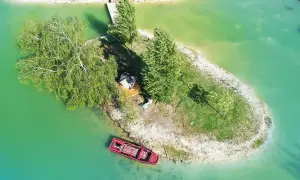 Un séjour insolite en Île-de-France : une petite île avec une cabane, un bateau rouge et un ponton.
