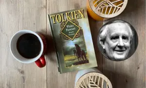 Kawa i książka "Władca Pierścieni" obok portretu J.R.R. Tolkiena. Krótka biografia pisarza inspiruje do podróży w świat fantasy.