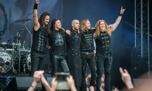 Zespół Beast in Black na koncercie, pięciu muzyków pozuje na scenie, pozdrawiając publiczność.