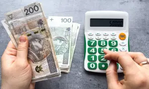 Ręka trzyma banknoty 200 zł i 100 zł, obok kalkulator z wyświetloną kwotą 50000. Czy to już minimalna krajowa?