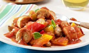 Herzhaftes Wurstgulasch mit Bratwurst, Tomaten und Pilzen, garniert mit frischen Kräutern. Ein deftiges Gericht für Genießer.