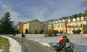 Zimowy krajobraz przed żółtym sanatorium. Zastanawiasz się, ile kosztuje turnus w sanatorium?