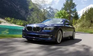 Granatowy BMW Alpina B7 mknie po górskiej drodze, obok turkusowego jeziora i ośnieżonych szczytów.