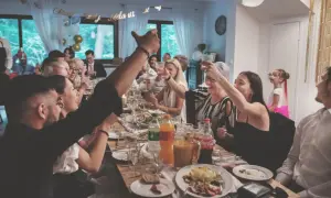 Radosne chrzciny w domu. Rodzina wznosi toasty przy suto zastawionym stole, świętując ważne wydarzenie.