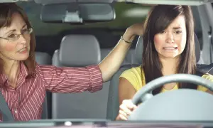 Mujer con amaxofobia, que es el miedo a conducir, se muestra angustiada mientras una mujer mayor le da instrucciones.