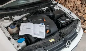 Otwarta maska samochodu z widocznym silnikiem 1.9 TDI, instrukcją obsługi i narzędziami.