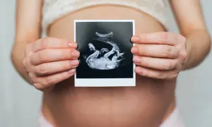 Dłoń kobiety trzyma zdjęcie USG z widocznym dzieckiem. Na zdjęciu widać łożysko na przedniej ścianie.