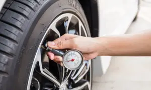 Main d'une personne vérifiant la pression d'un pneu avec un manomètre. Essentiel pour la réglementation pneu poids lourd et la sécurité routière.