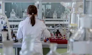 Naukowczyni w białym fartuchu analizuje próbki, badając wskaźnik anizocytozy erytrocytów wśród laboratoryjnego sprzętu.