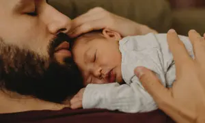 En pappa tröstar sin bebis som gråter hela tiden. Bebisen sover lugnt mot pappans bröst.