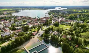 Widok na Ryn z lotu ptaka. Widać jezioro, miasto, plażę i basen. To świetne miejsce na wakacje, pełne atrakcji dla dzieci.