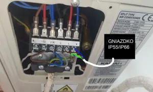 Podłączenie elektryczne klimatyzacji. Widoczne zaciski śrubowe z przewodami fazowymi (L), neutralnym (N) i uziemiającym (zielono-żółty). Gniazdko IP55/IP66.