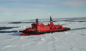 Ein rotes Eisbrecher-Schiff mit Haifischzähnen am Bug kämpft sich durch gefrorenes Wasser.