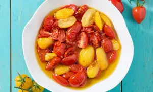 Pomodorini confit in friggitrice ad aria, rossi e gialli, immersi in olio profumato, pronti per insaporire ogni piatto.